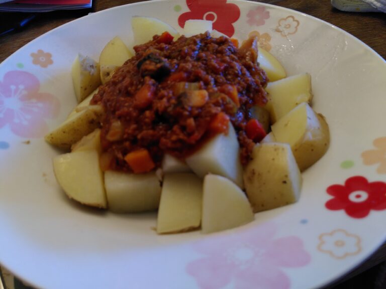 A bowl of vegan bolognese served over steamed new potatoes