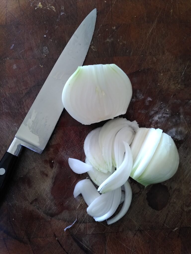 Knife on a chopping block with a sliced onion