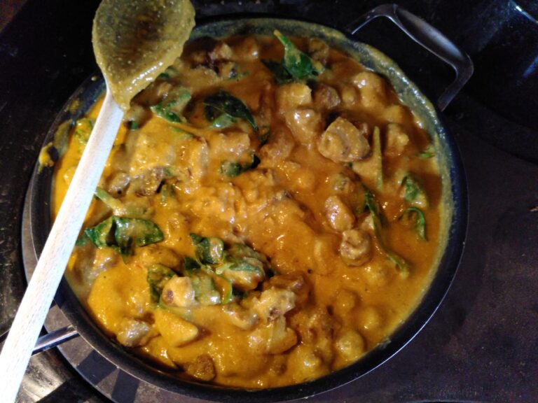 A pan of potato and spinach curry simmering on the wood burning range top