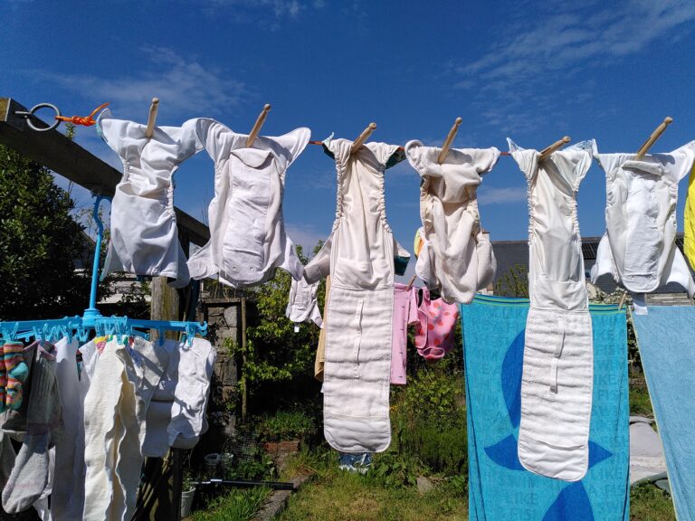 A row of reusable nappies drying outside on a washing line on a sunny day.