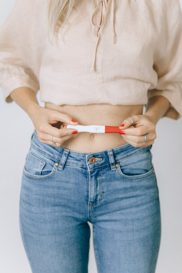 Women holding a positive pregnancy test in front of her abdomen