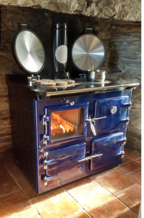 A wood fired range cooker in the fireplace of a farmhouse kitchen.