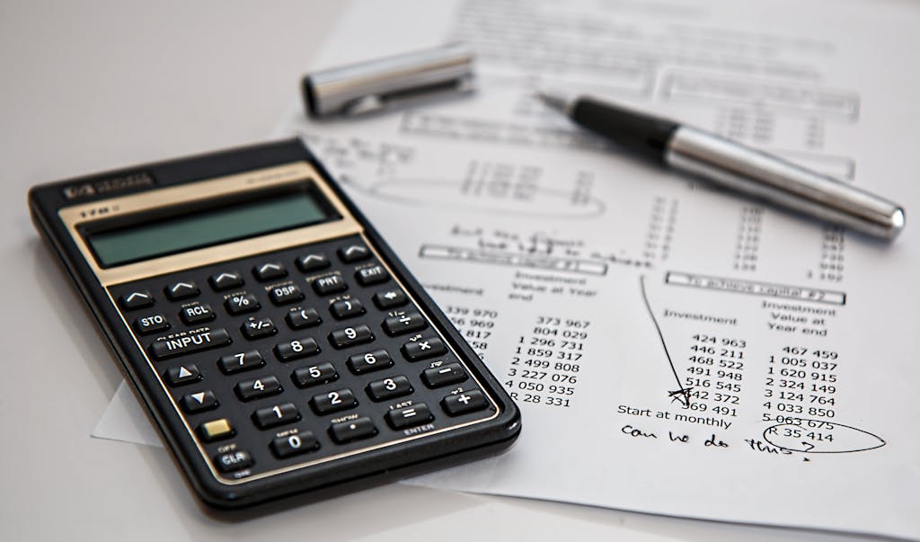 Black Calculator Near Ballpoint Pen on White Printed Paper Planning Out Budget