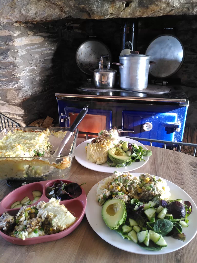 Vegan fishy pie, served with a green salad. Photographed in the worktop of a farmhouse kitchen, in front of a woodburning range.