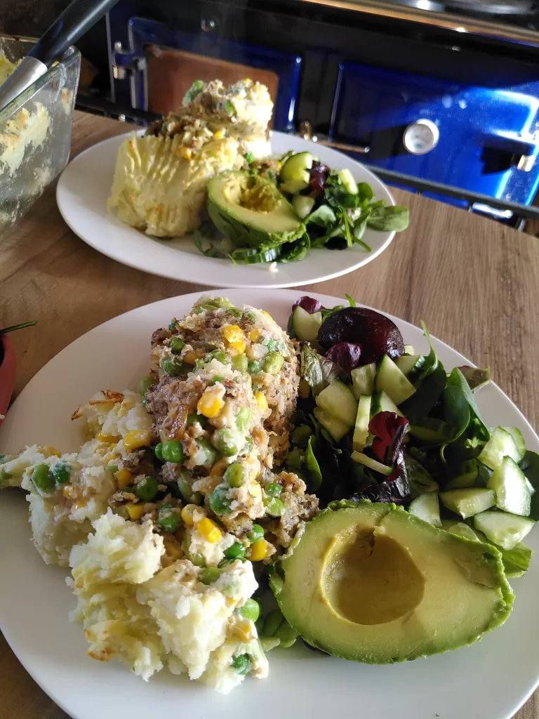 Two plates of vegan fishy pie accompanied by a green salad.